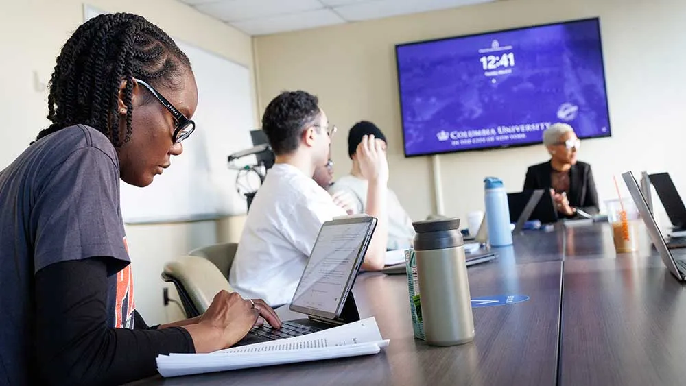 student in a graduate level classroom with other students