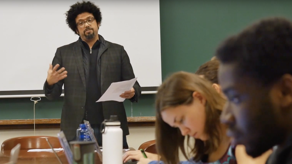Man with glasses teaching in front of a class of students