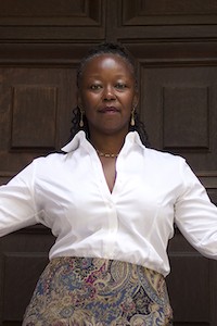 Farah Jasmine Griffin. Photo Credit: Ann Blake Woman with white shirt in front of a door with arms outstretched