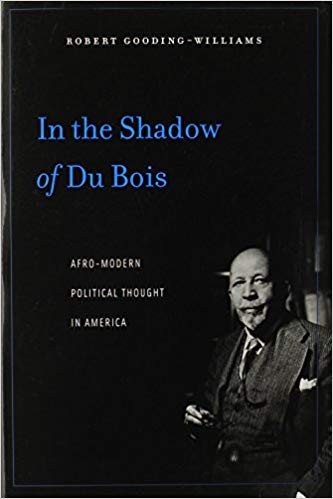W.E.B.Dubois, wearing a suit, sits in a darkened room; the image is further darkened to convey foreshadowing