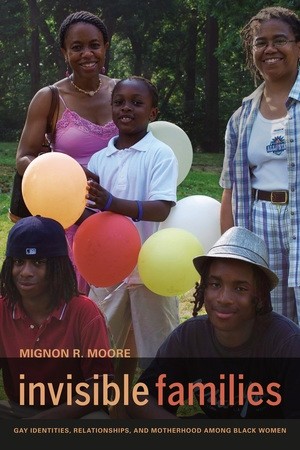 Two women, smiling, stand with three children holding balloons in a park